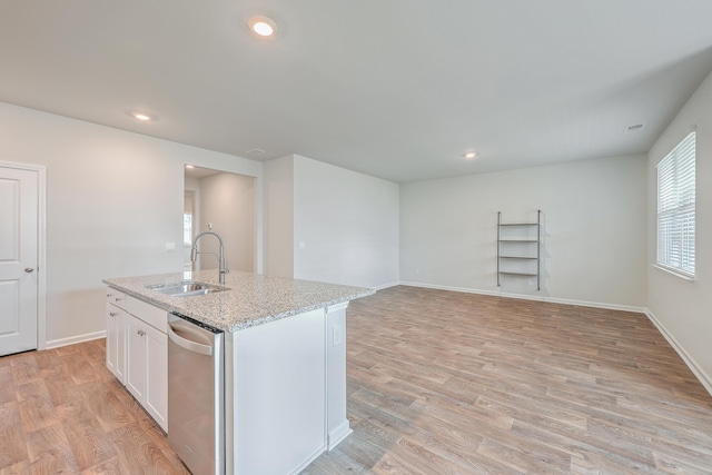 kitchen with light stone countertops, dishwasher, white cabinetry, sink, and a kitchen island with sink