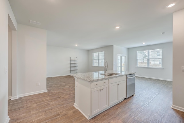 kitchen with white cabinetry, an island with sink, light hardwood / wood-style flooring, light stone counters, and sink