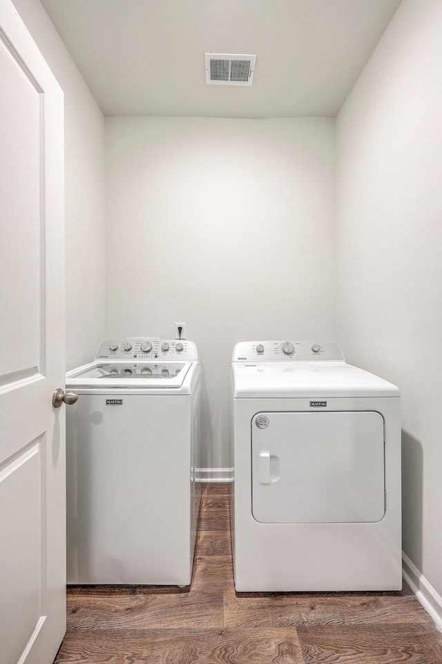 clothes washing area with dark hardwood / wood-style flooring and washer and dryer