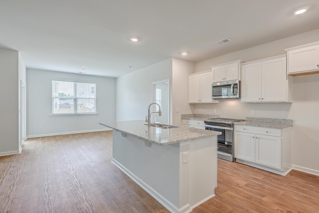 kitchen with white cabinets, a kitchen island with sink, sink, and stainless steel appliances