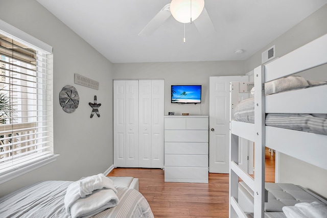 bedroom featuring ceiling fan, a closet, visible vents, and wood finished floors