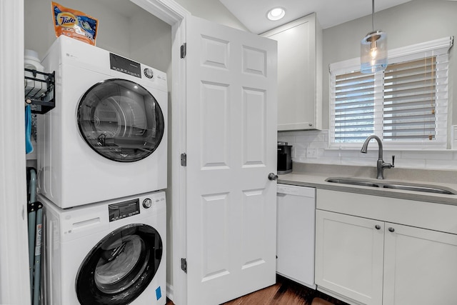 clothes washing area featuring laundry area, a sink, dark wood finished floors, and stacked washer / drying machine