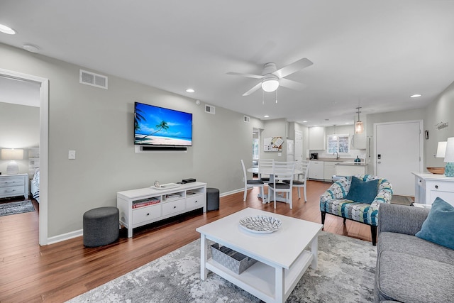 living area with recessed lighting, visible vents, baseboards, and wood finished floors