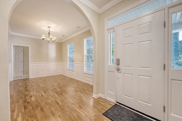 1308 Wild Olive Dr, Mount Pleasant, SC 29464 - entryway featuring arched walkways, light wood-type flooring, a chandelier, ornamental molding, and a wainscoted wall
