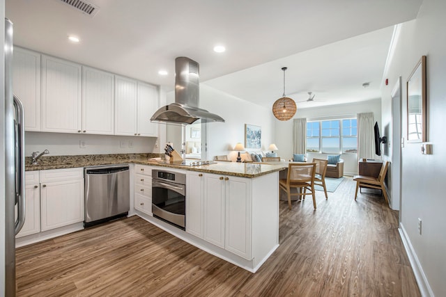 kitchen featuring white cabinets, light hardwood / wood-style flooring, island range hood, kitchen peninsula, and stainless steel appliances