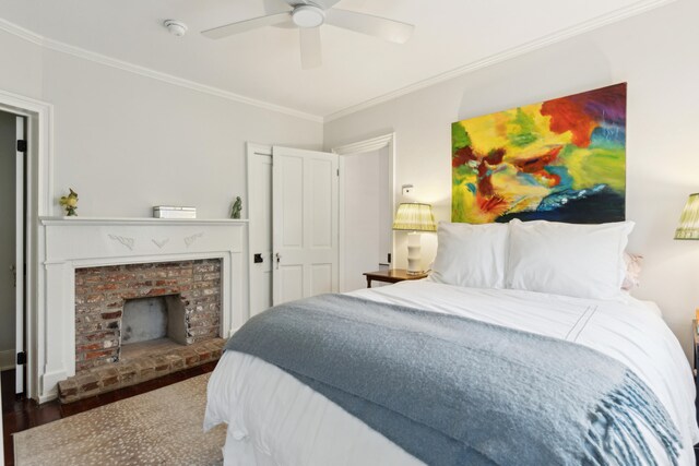 bedroom featuring a brick fireplace, ceiling fan, dark hardwood / wood-style flooring, and ornamental molding