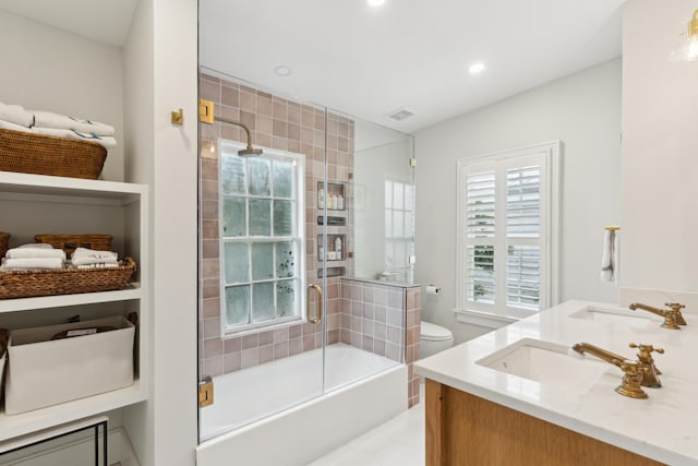 full bathroom featuring shower / bath combination with glass door, vanity, toilet, and plenty of natural light