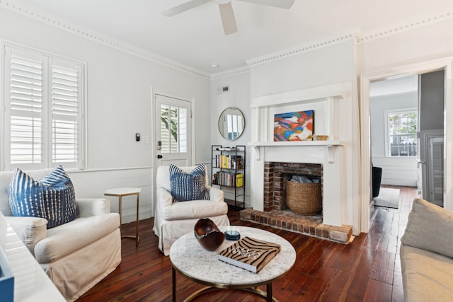 living room with a brick fireplace, a wealth of natural light, dark wood-type flooring, and ceiling fan