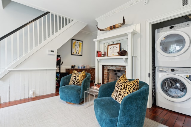 laundry area with stacked washer / dryer, wood-type flooring, wooden walls, a fireplace, and ornamental molding