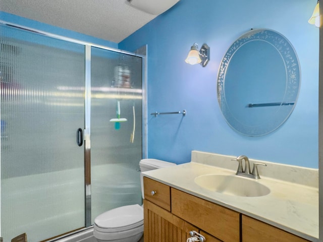 bathroom with vanity, toilet, a shower with shower door, and a textured ceiling