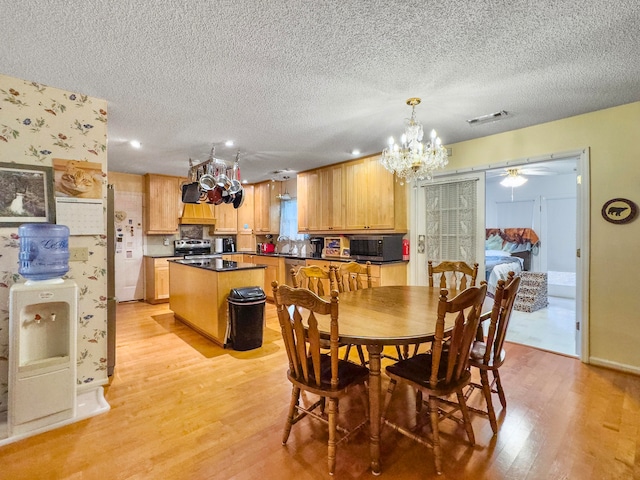 dining area with a textured ceiling, ceiling fan with notable chandelier, and light wood-type flooring