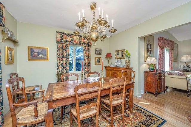 dining area with a chandelier, light wood-type flooring, and lofted ceiling