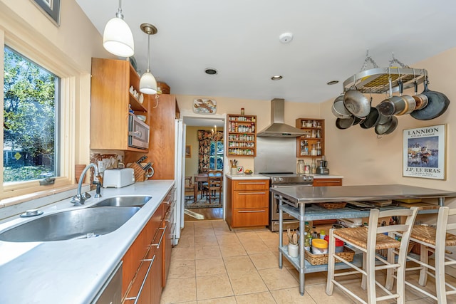 kitchen with stainless steel electric stove, sink, wall chimney exhaust hood, and a healthy amount of sunlight