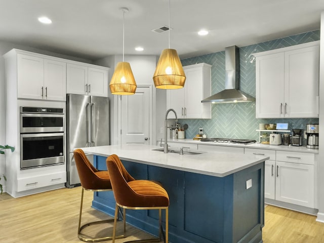 kitchen with stainless steel appliances, sink, white cabinets, and wall chimney exhaust hood