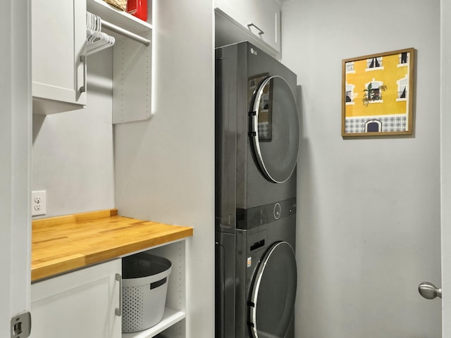 laundry area with stacked washer / dryer and cabinets