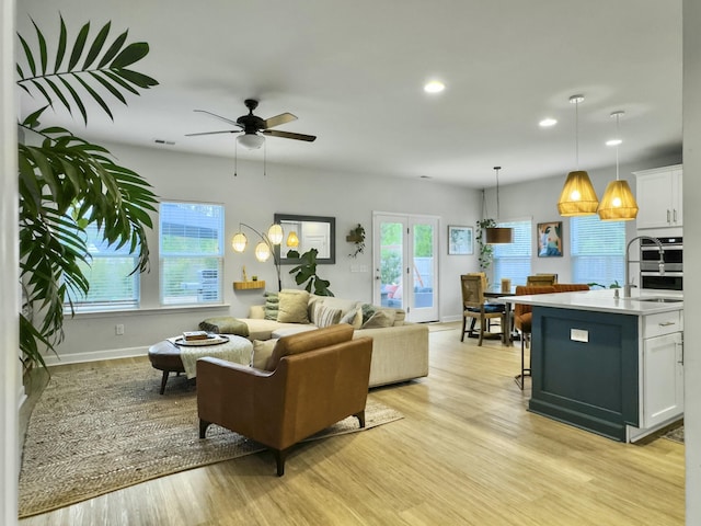 living room with ceiling fan, sink, light hardwood / wood-style floors, and a wealth of natural light