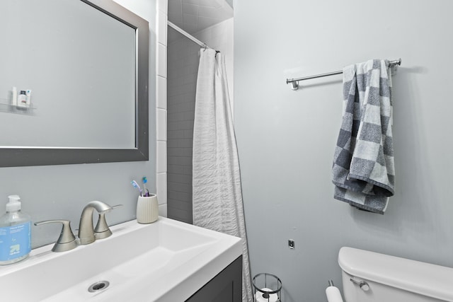 bathroom with tiled shower, vanity, and toilet