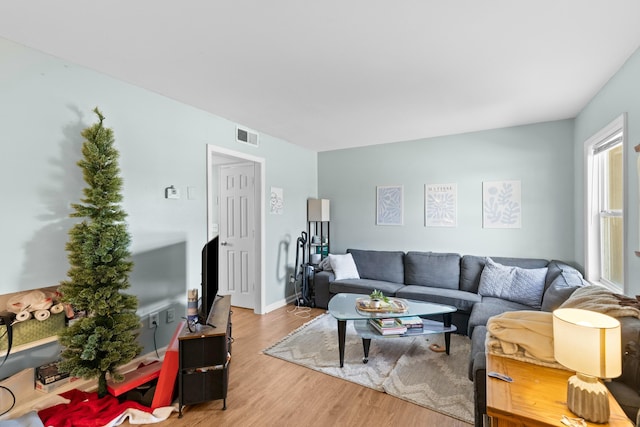 living room featuring baseboards, visible vents, and wood finished floors