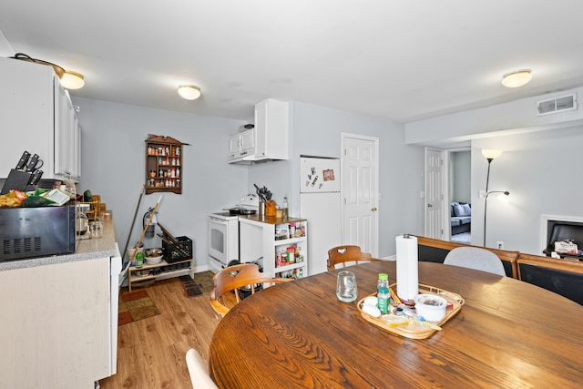 dining room featuring light wood finished floors, visible vents, and baseboards