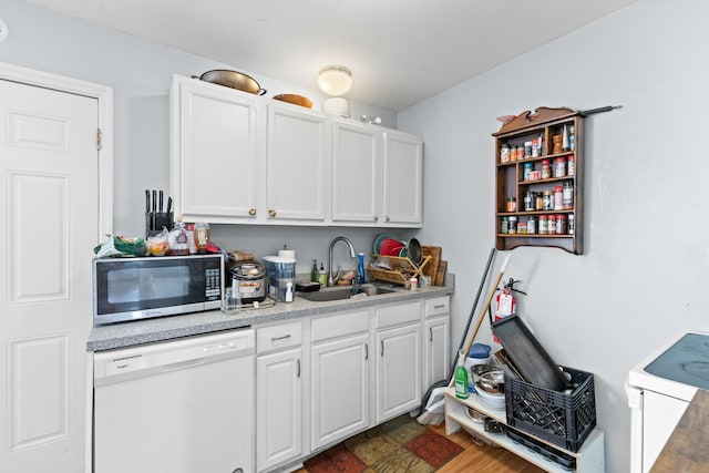 kitchen featuring white appliances, a sink, white cabinets, light countertops, and dark wood finished floors