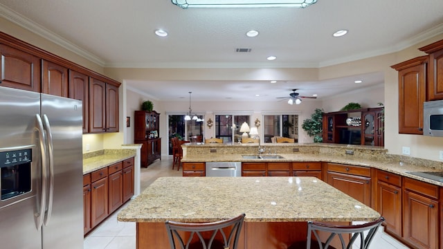 kitchen featuring appliances with stainless steel finishes, a peninsula, a center island, light tile patterned floors, and light stone counters