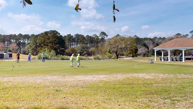 view of home's community featuring golf course view, a gazebo, a yard, and view of wooded area
