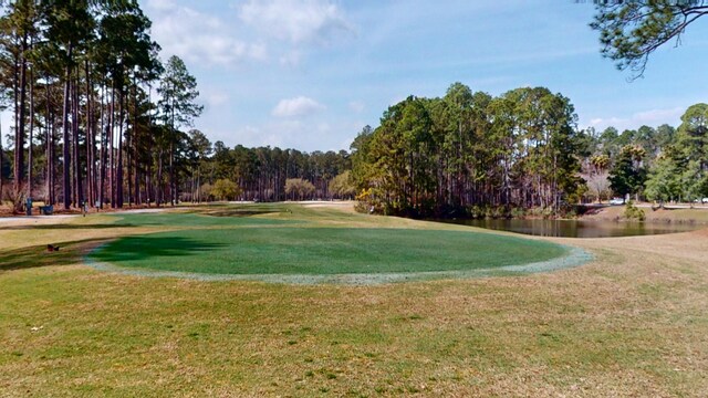 view of property's community featuring a water view, a lawn, and view of golf course