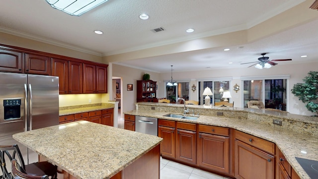 kitchen with appliances with stainless steel finishes, a kitchen bar, light stone counters, crown molding, and a ceiling fan