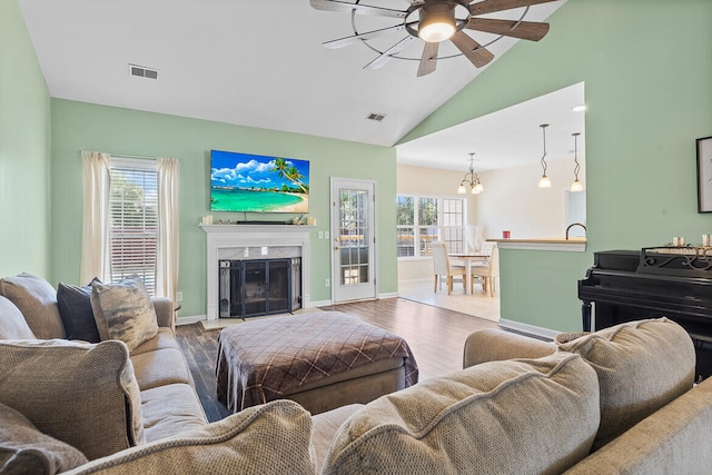 living area featuring plenty of natural light, visible vents, a fireplace with raised hearth, and wood finished floors