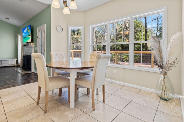 dining area with a wealth of natural light, a fireplace, and light tile patterned floors