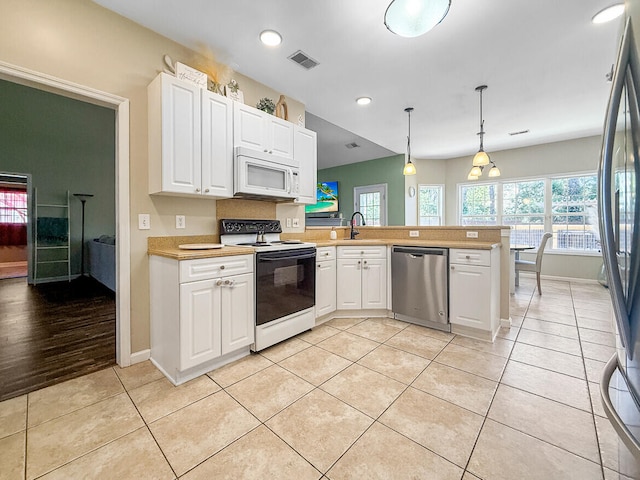 kitchen featuring light tile patterned flooring, a peninsula, visible vents, light countertops, and appliances with stainless steel finishes