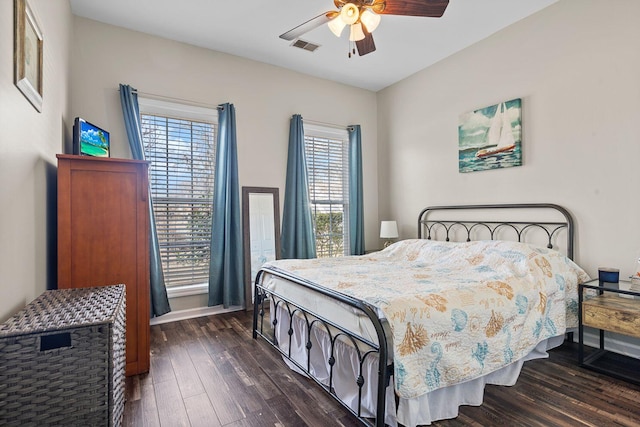 bedroom with a ceiling fan, visible vents, and dark wood-type flooring