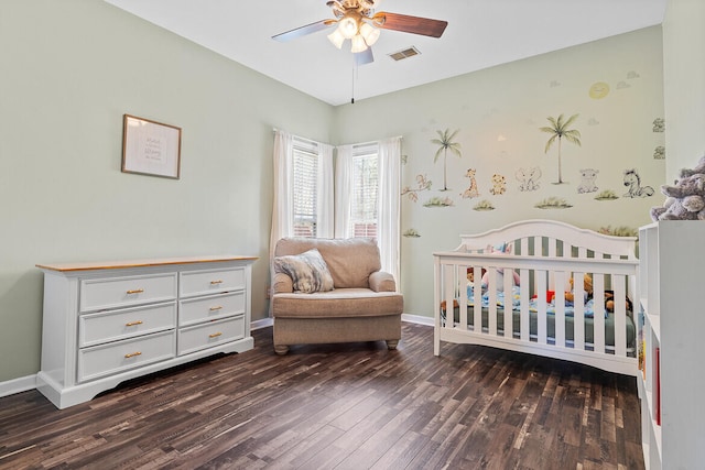 bedroom featuring visible vents, a ceiling fan, wood finished floors, a nursery area, and baseboards