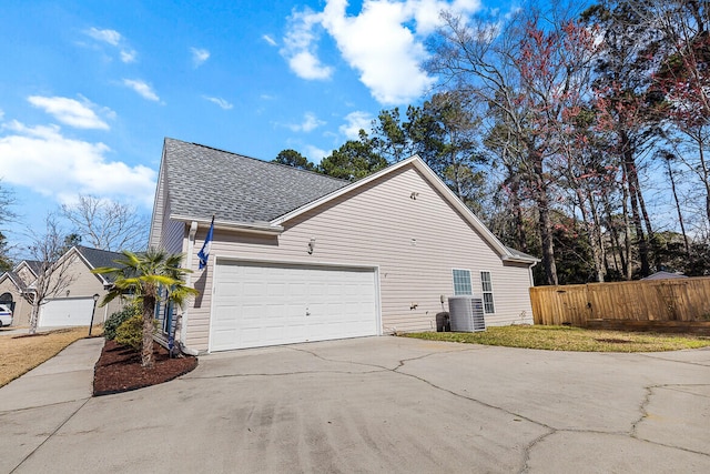 view of home's exterior featuring a garage, central AC, fence, concrete driveway, and roof with shingles