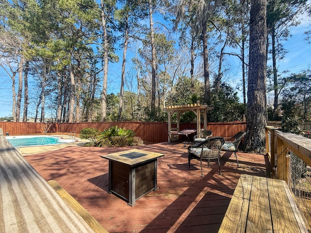 wooden terrace with an outdoor fire pit, a pergola, a fenced in pool, and a fenced backyard