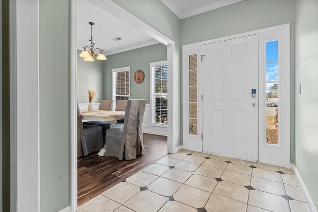 entryway featuring ornamental molding, light wood finished floors, baseboards, and an inviting chandelier