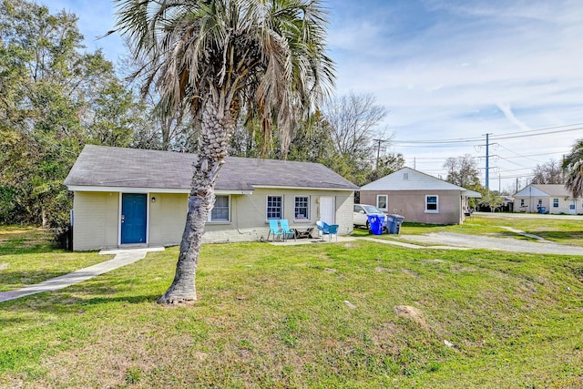 single story home with a front yard, a patio area, and concrete block siding