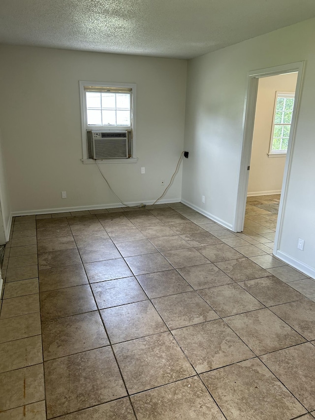 tiled spare room featuring cooling unit, a textured ceiling, and baseboards