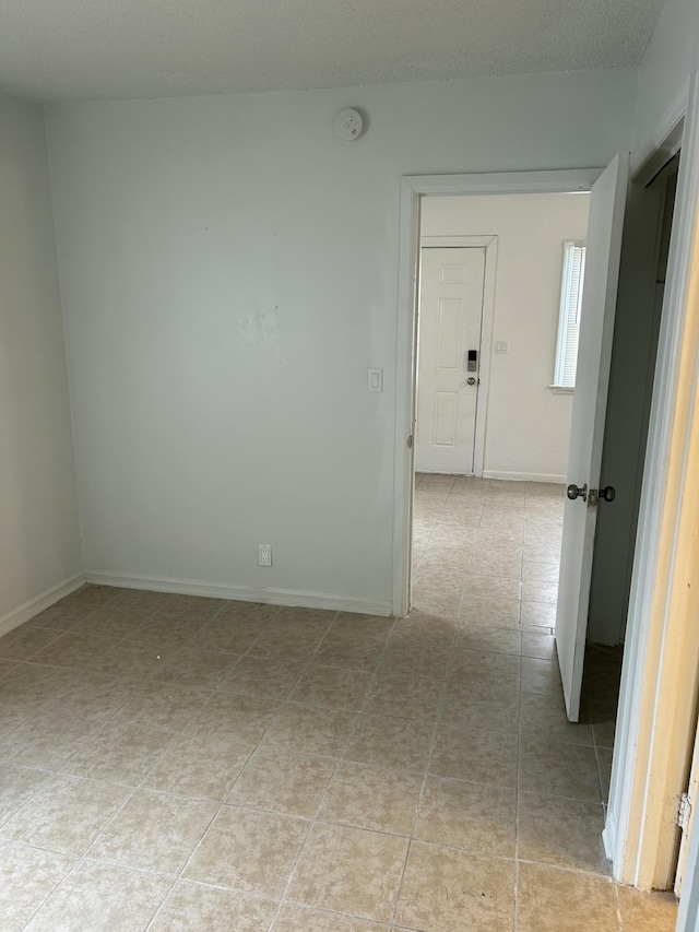 empty room with light tile patterned floors and baseboards
