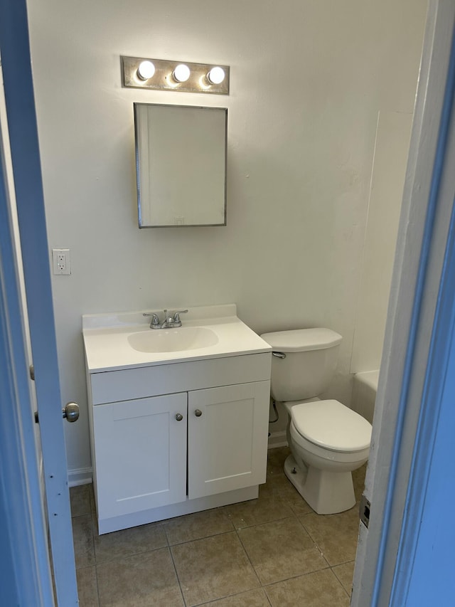 bathroom featuring toilet, tile patterned floors, vanity, and a washtub