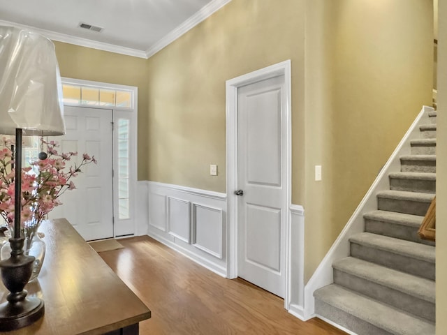 entrance foyer featuring wood-type flooring, ornamental molding, and a wealth of natural light