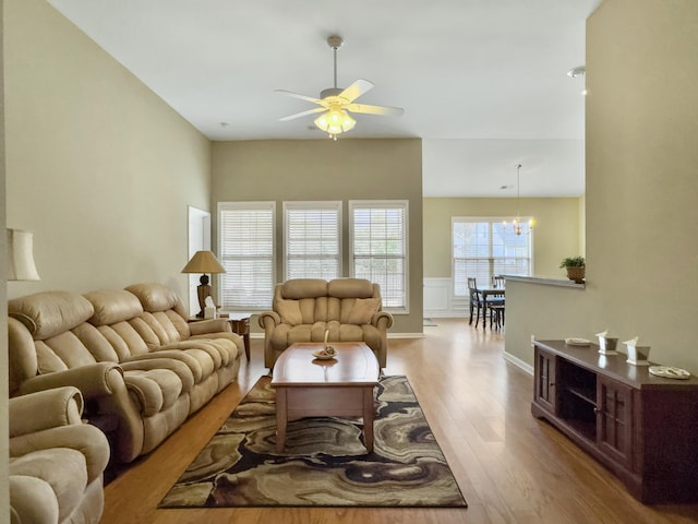 living room with ceiling fan with notable chandelier and light wood-type flooring