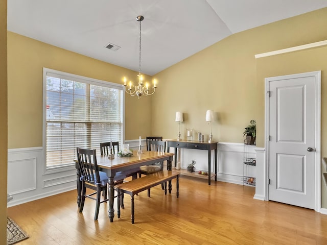 dining space featuring a chandelier, lofted ceiling, and light hardwood / wood-style flooring