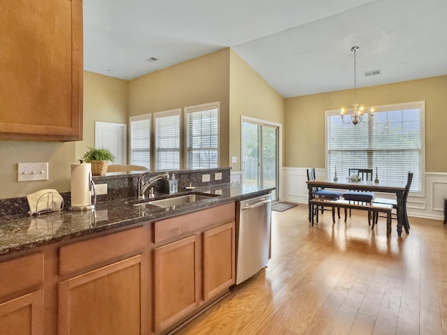 kitchen with sink, hanging light fixtures, stainless steel dishwasher, dark stone counters, and a chandelier