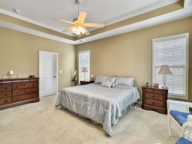 bedroom with a raised ceiling, ceiling fan, and light colored carpet