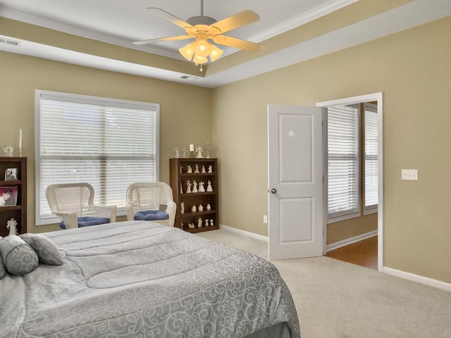 carpeted bedroom featuring multiple windows, a tray ceiling, ceiling fan, and crown molding