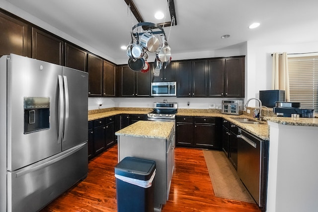 kitchen featuring light stone countertops, appliances with stainless steel finishes, sink, kitchen peninsula, and dark hardwood / wood-style floors