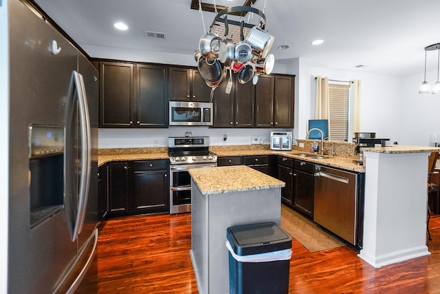 kitchen with sink, a kitchen island, appliances with stainless steel finishes, and dark hardwood / wood-style flooring