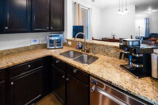 kitchen with light stone countertops, sink, dishwasher, kitchen peninsula, and pendant lighting