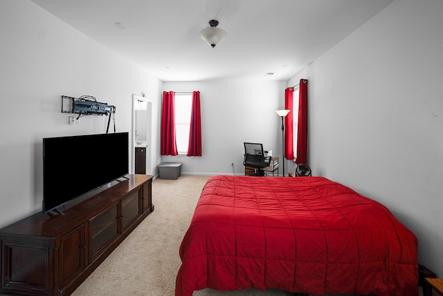 bedroom with connected bathroom and light carpet